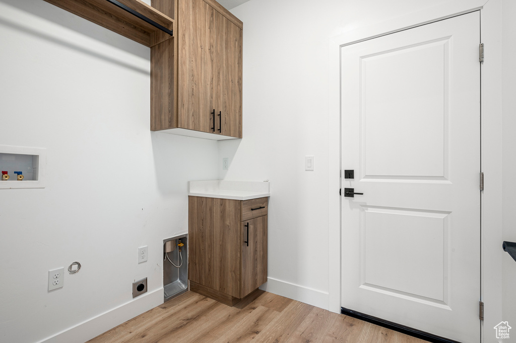 Laundry area with light hardwood / wood-style flooring, cabinets, hookup for a washing machine, and hookup for an electric dryer