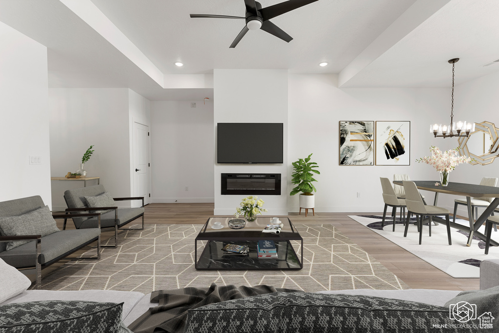 Living room with ceiling fan with notable chandelier and hardwood / wood-style flooring