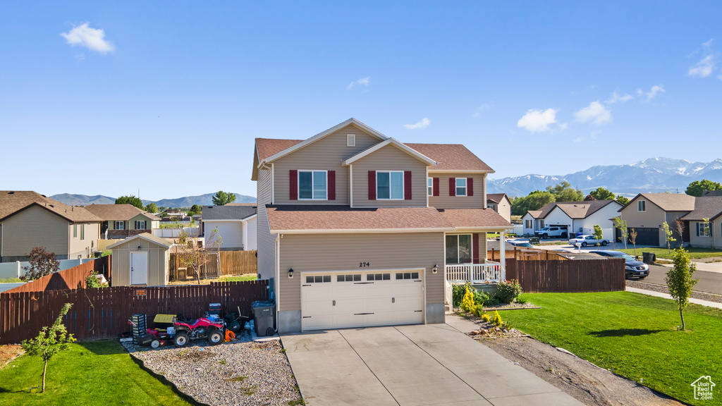 View of property featuring a front lawn, a garage, and a mountain view