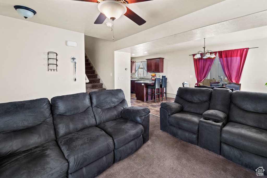 Carpeted living room featuring ceiling fan with notable chandelier