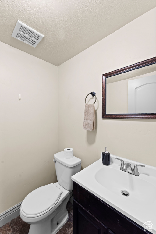 Bathroom featuring tile flooring, vanity, toilet, and a textured ceiling