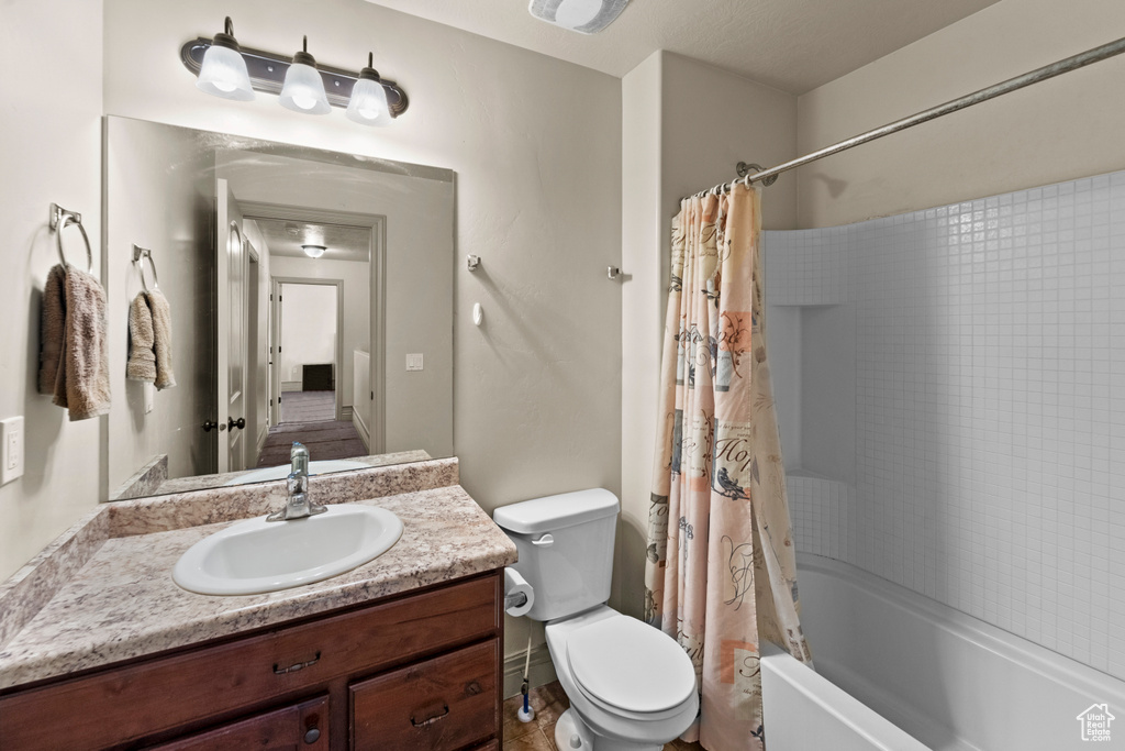 Full bathroom with tile floors, shower / bath combo, toilet, and vanity