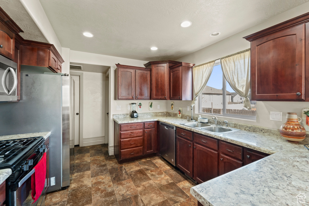 Kitchen featuring stainless steel appliances, sink, and dark tile floors