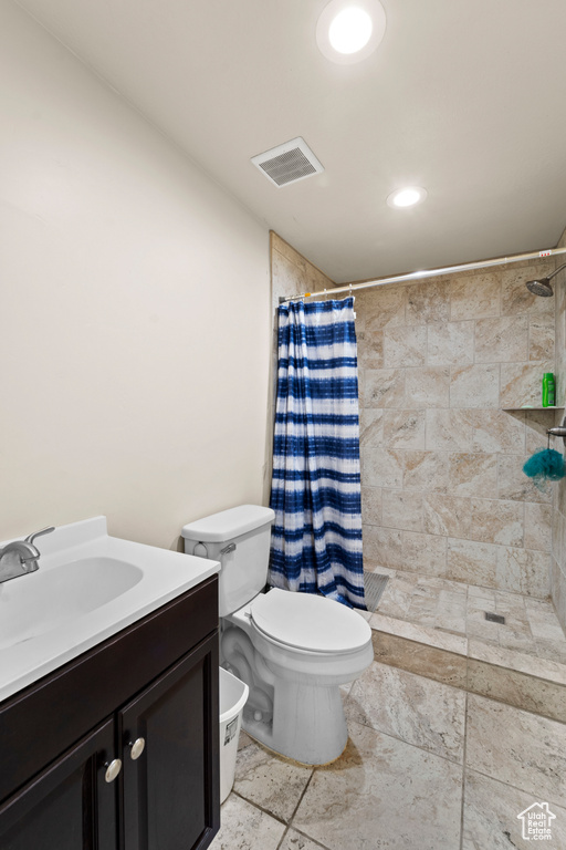 Bathroom featuring tile floors, a shower with shower curtain, vanity, and toilet