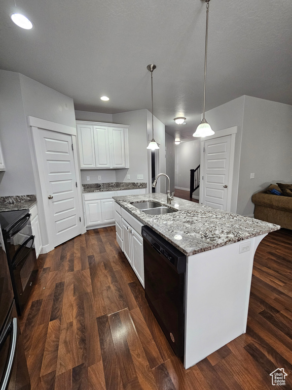 Kitchen featuring a kitchen island with sink, dark wood-type flooring, black appliances, and pendant lighting