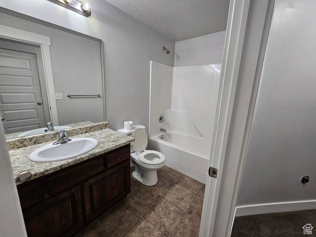 Full bathroom with oversized vanity, a textured ceiling, tile floors, shower / bath combination, and toilet