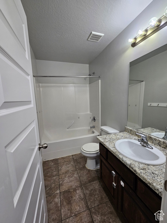 Full bathroom with a textured ceiling, tile floors,  shower combination, vanity, and toilet