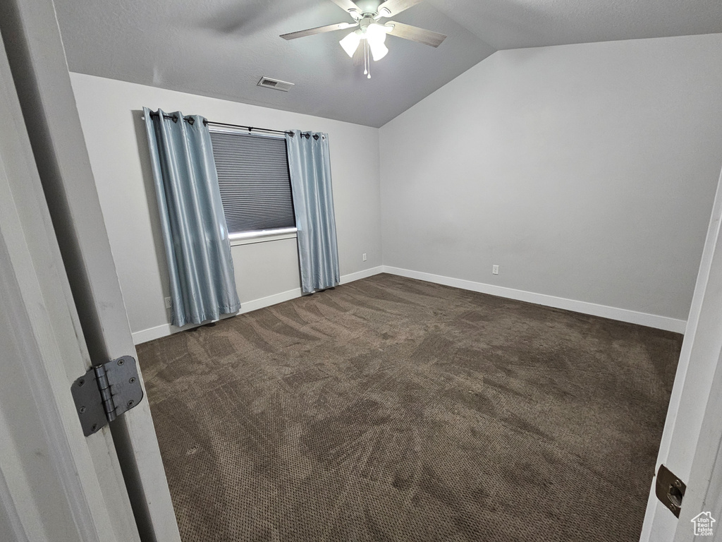 Carpeted spare room with ceiling fan and lofted ceiling