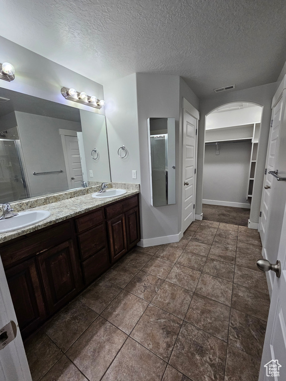 Bathroom with oversized vanity, double sink, a textured ceiling, and tile floors