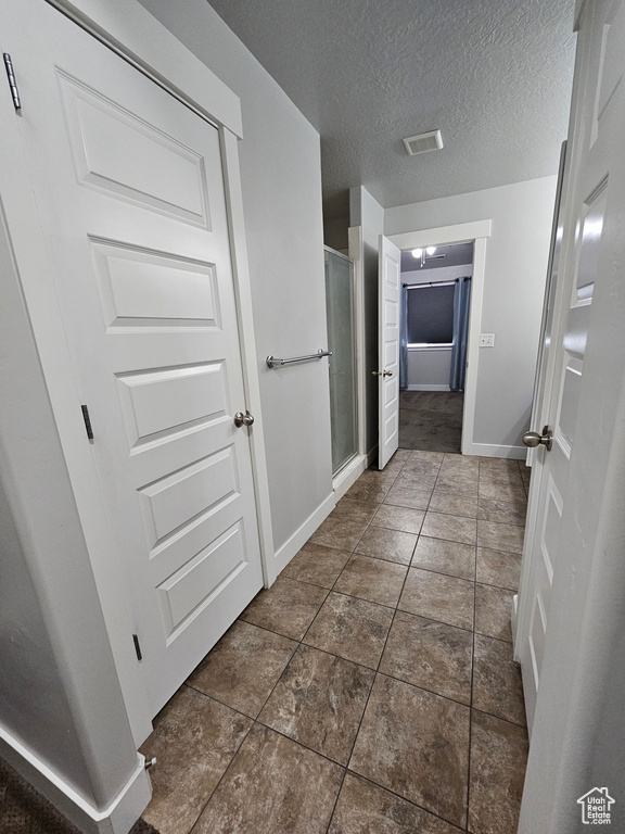 Hallway with dark tile flooring and a textured ceiling