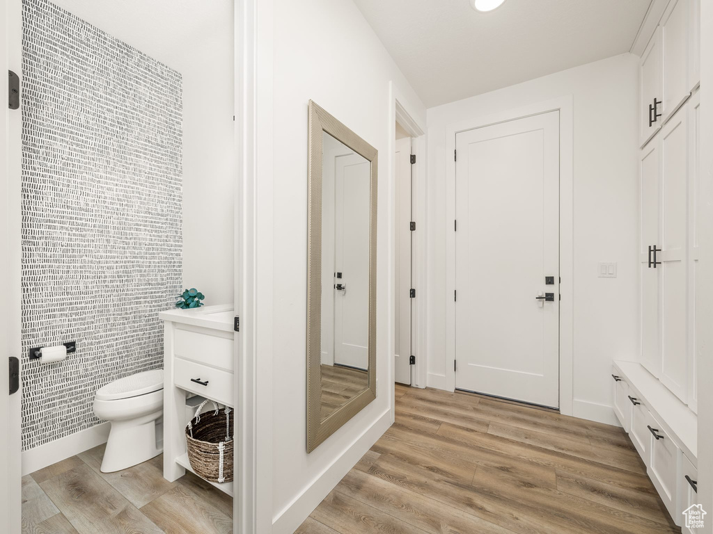 Bathroom with hardwood / wood-style floors, vanity, toilet, and tile walls