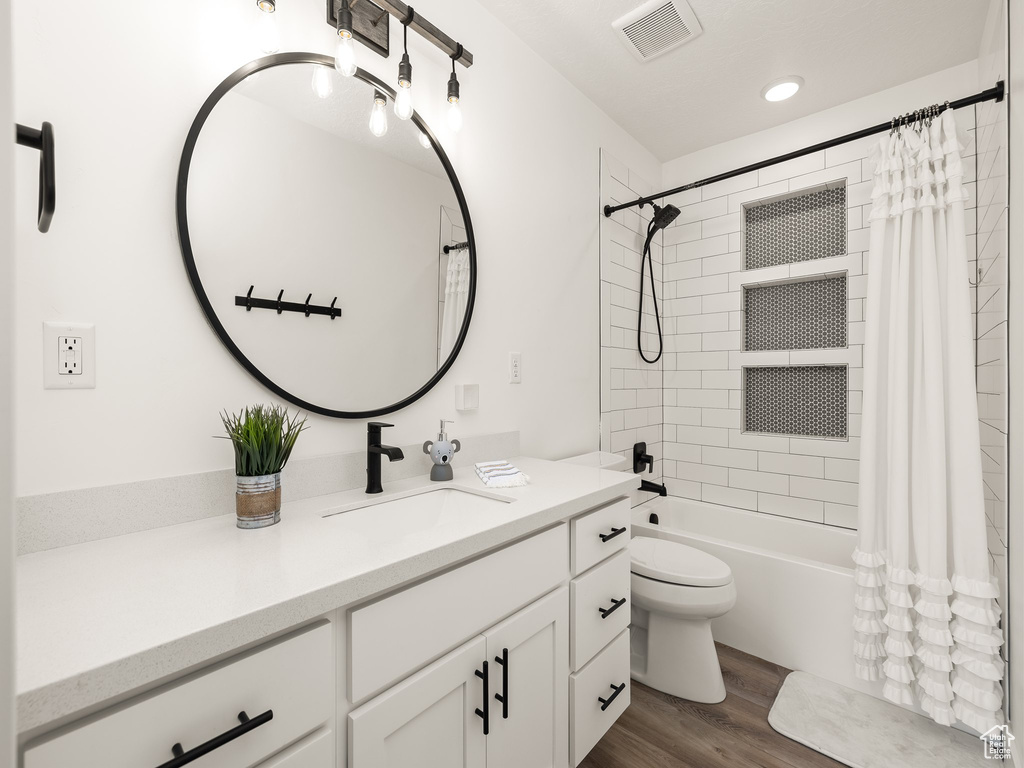 Full bathroom with wood-type flooring, vanity, toilet, and shower / tub combo