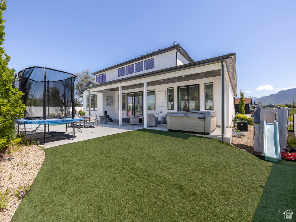 Back of property featuring outdoor lounge area, a yard, a patio area, a shed, and a trampoline