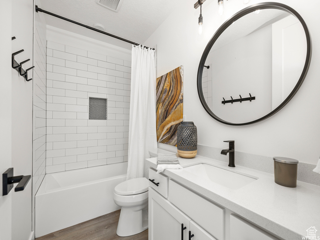 Full bathroom featuring toilet, hardwood / wood-style flooring, shower / bath combo with shower curtain, and vanity