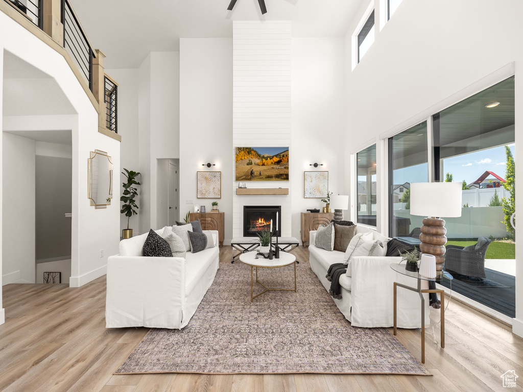 Living room with a towering ceiling, a large fireplace, and light hardwood / wood-style flooring