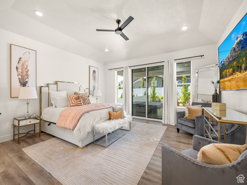 Bedroom featuring ceiling fan, hardwood / wood-style flooring, access to exterior, and lofted ceiling