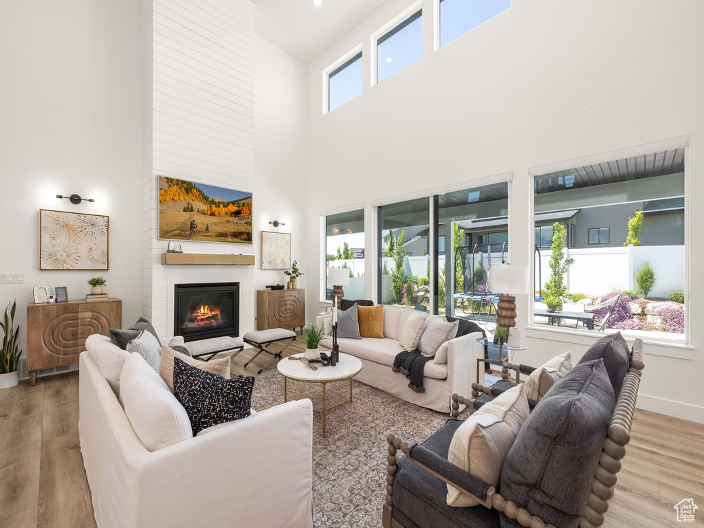 Living room featuring a high ceiling, a fireplace, and wood-type flooring