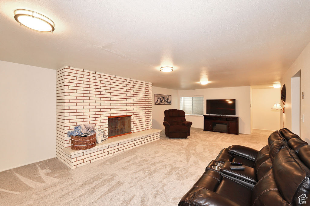 Carpeted living room featuring brick wall, a brick fireplace, and a textured ceiling