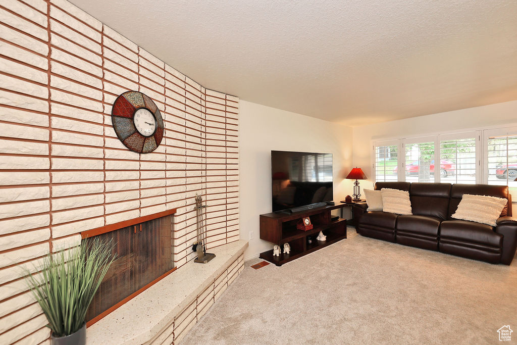 Living room with a fireplace, carpet, and a textured ceiling