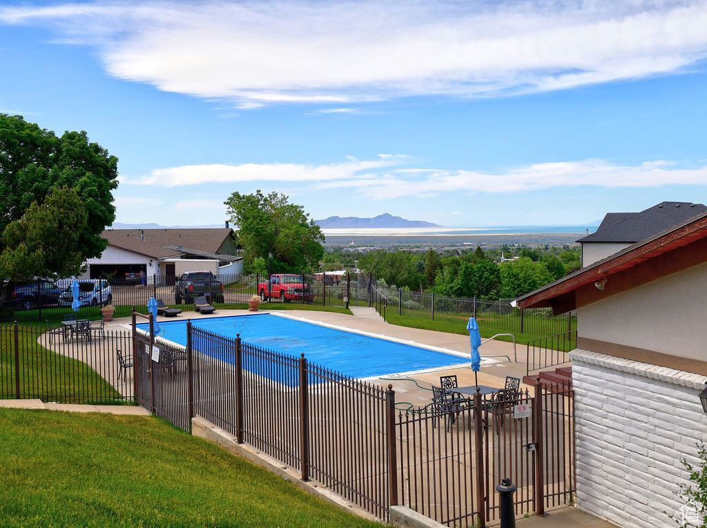 View of swimming pool featuring a patio, a yard, and a mountain view