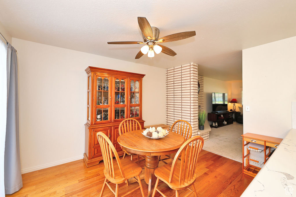 Dining room featuring brick wall, ceiling fan, and light wood-type flooring