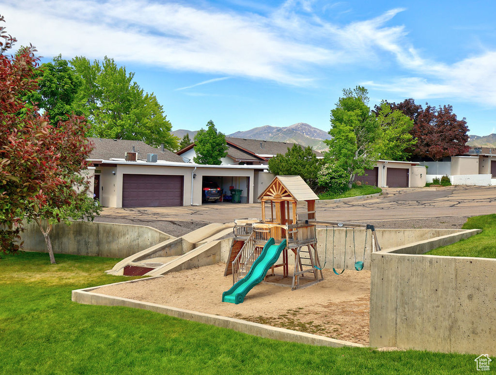 View of jungle gym featuring a mountain view and a lawn