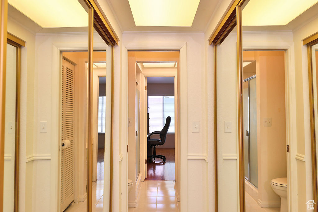 Hallway with light hardwood / wood-style flooring and crown molding