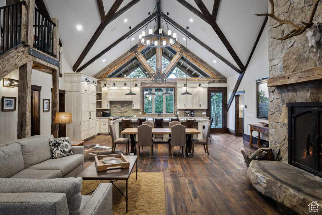 Living room with high vaulted ceiling, beamed ceiling, hardwood / wood-style floors, and a stone fireplace