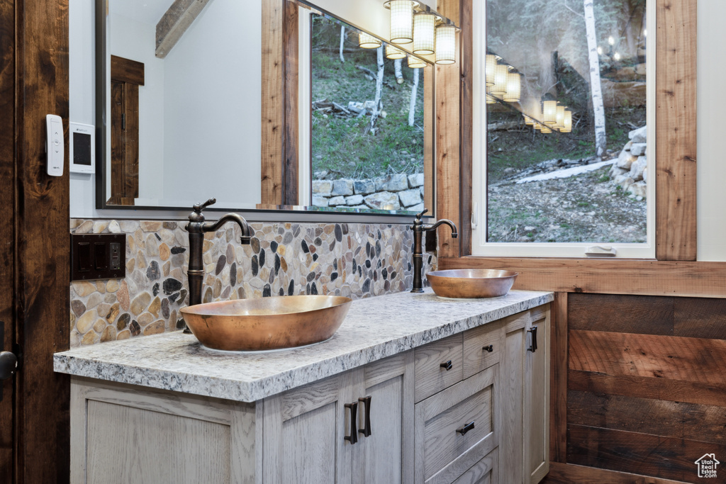 Bathroom with backsplash, oversized vanity, double sink, and plenty of natural light