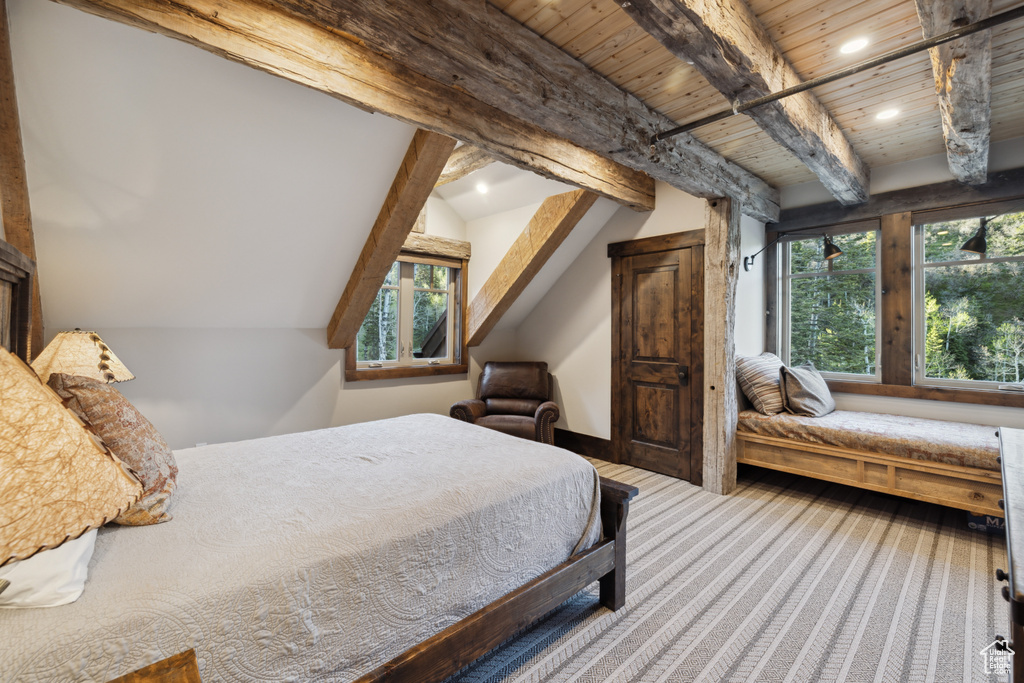 Carpeted bedroom with vaulted ceiling with beams and wooden ceiling