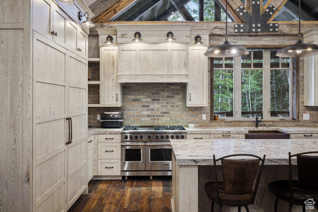 Kitchen with double oven range, sink, hanging light fixtures, and dark hardwood / wood-style floors