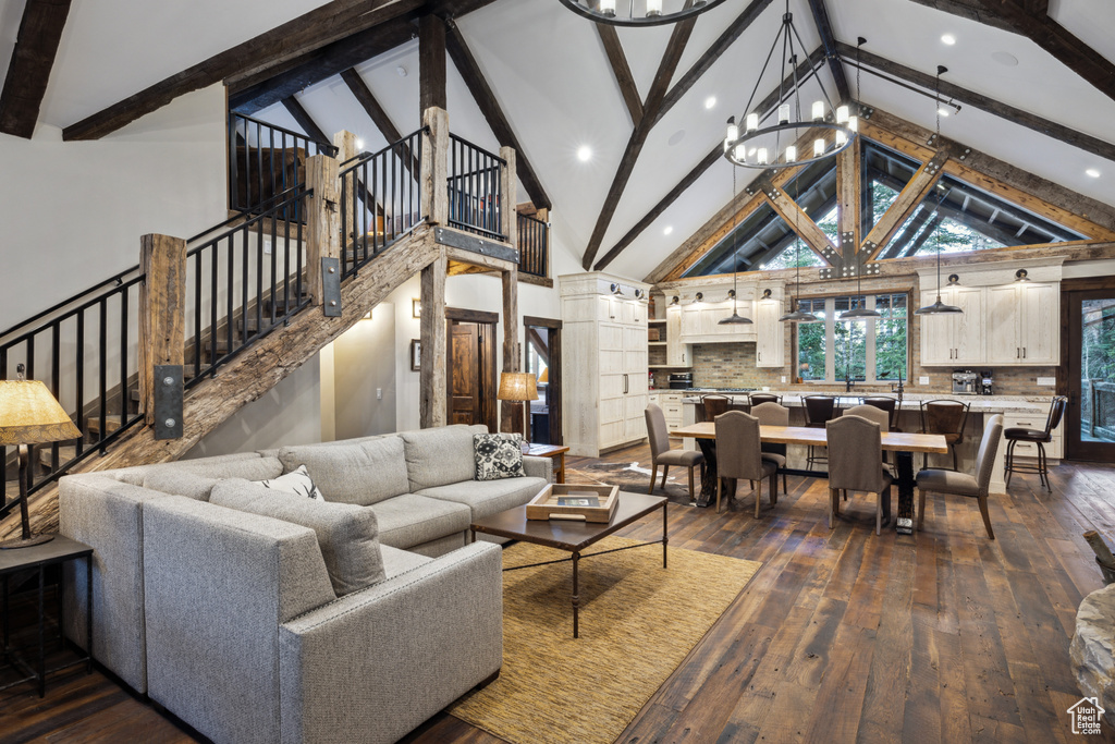 Living room featuring beam ceiling, high vaulted ceiling, hardwood / wood-style flooring, and a notable chandelier