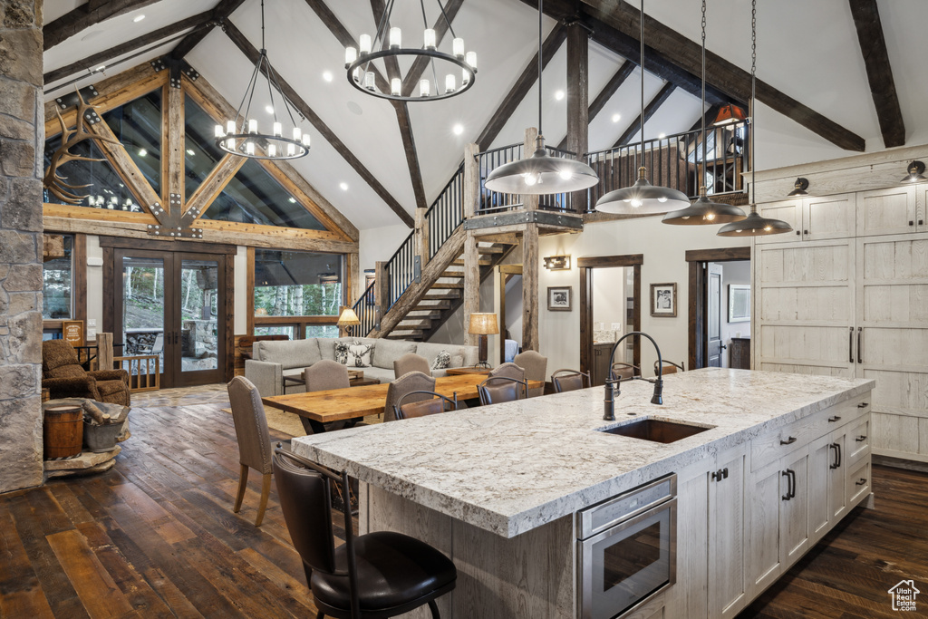 Kitchen with dark hardwood / wood-style floors, a kitchen island with sink, high vaulted ceiling, sink, and built in microwave