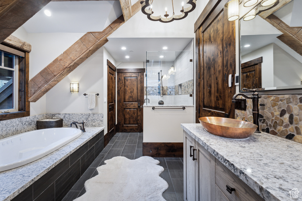 Bathroom featuring tile floors, tiled bath, a chandelier, and vanity with extensive cabinet space