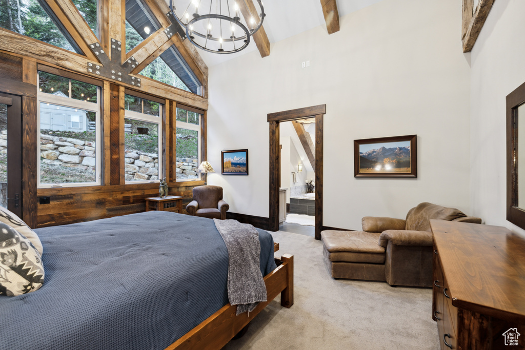 Bedroom with beamed ceiling, a chandelier, ensuite bath, carpet floors, and high vaulted ceiling