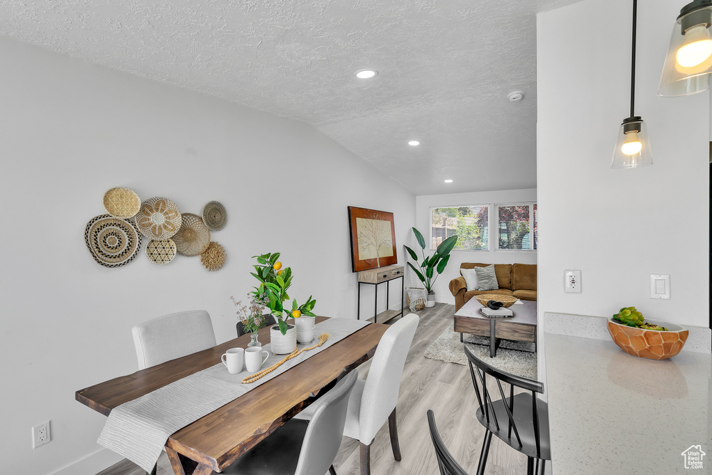 Dining room with vaulted ceiling, a textured ceiling, and wood-type flooring