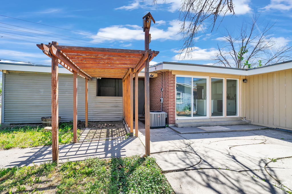 Rear view of property featuring a patio area, a pergola, and central air condition unit