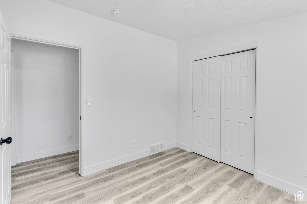 Unfurnished bedroom featuring a closet and light hardwood / wood-style flooring