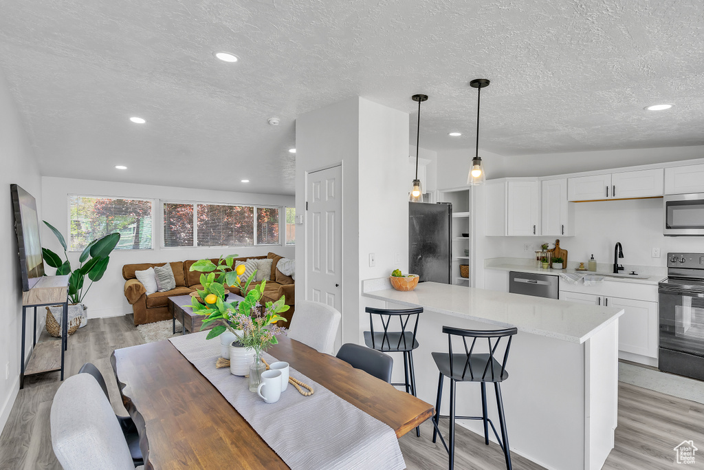 Dining room featuring sink, vaulted ceiling, a textured ceiling, and light wood-type flooring