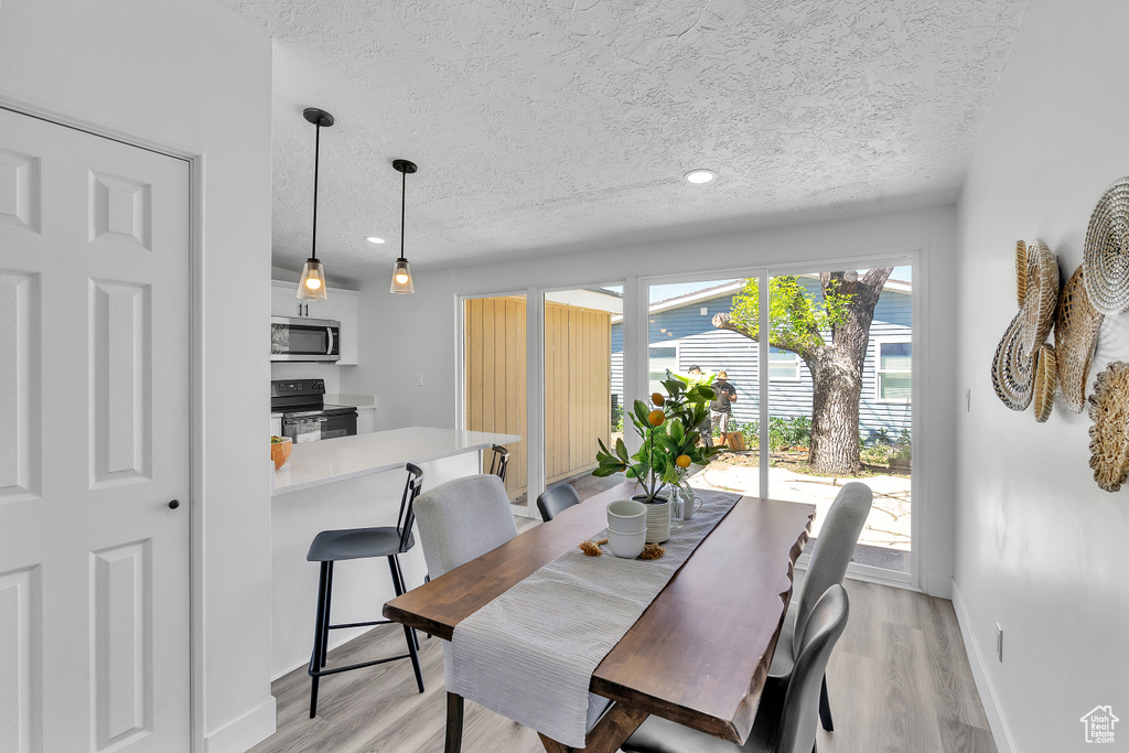 Dining area featuring a textured ceiling and light wood-type flooring