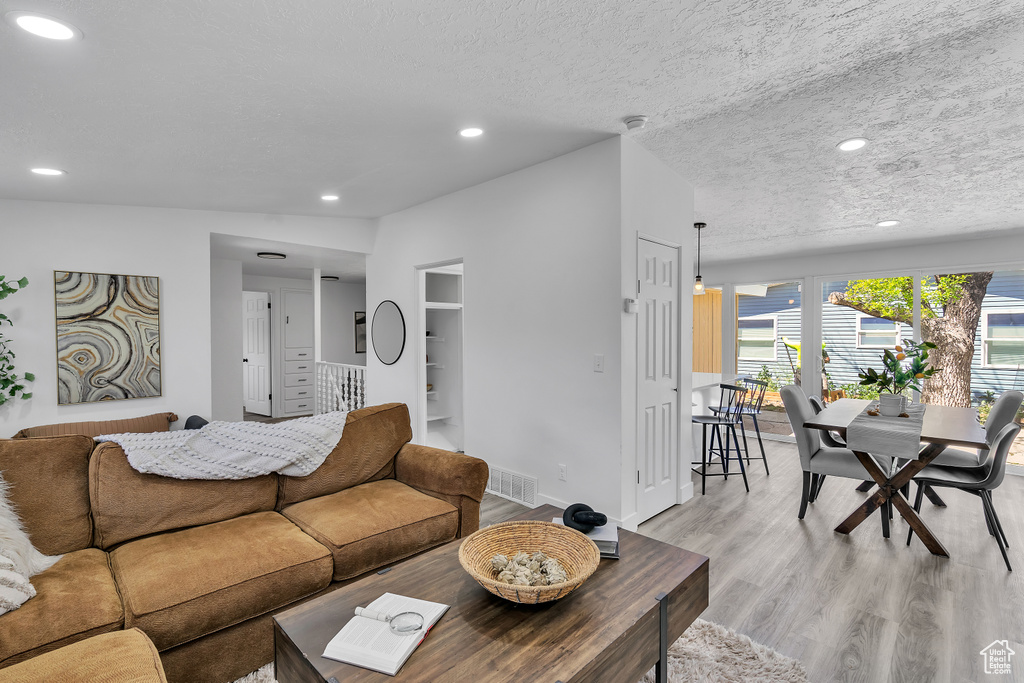 Living room with built in shelves, a textured ceiling, and light wood-type flooring