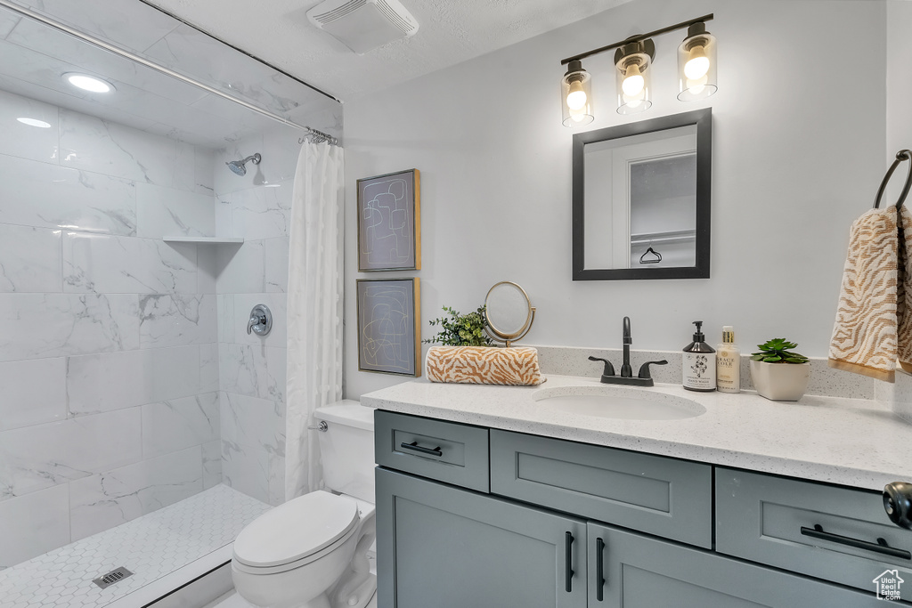 Bathroom with vanity, toilet, and a shower with shower curtain