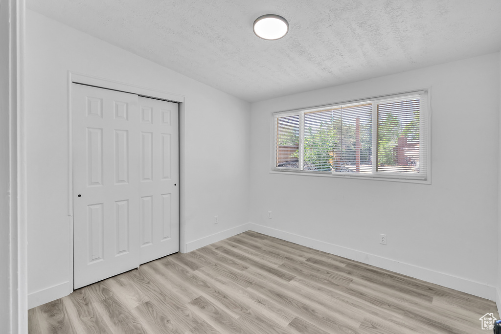 Unfurnished bedroom featuring a closet, light hardwood / wood-style flooring, and vaulted ceiling