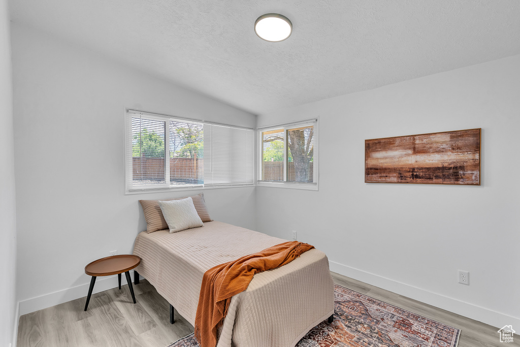 Bedroom with vaulted ceiling and light hardwood / wood-style flooring