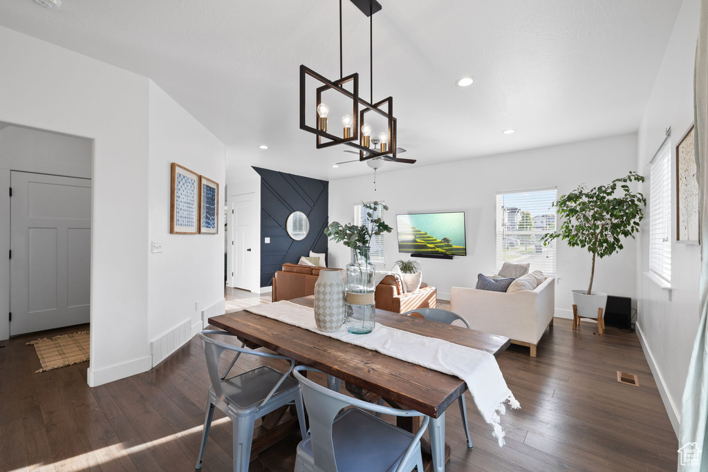 Dining room with dark hardwood / wood-style floors and a notable chandelier