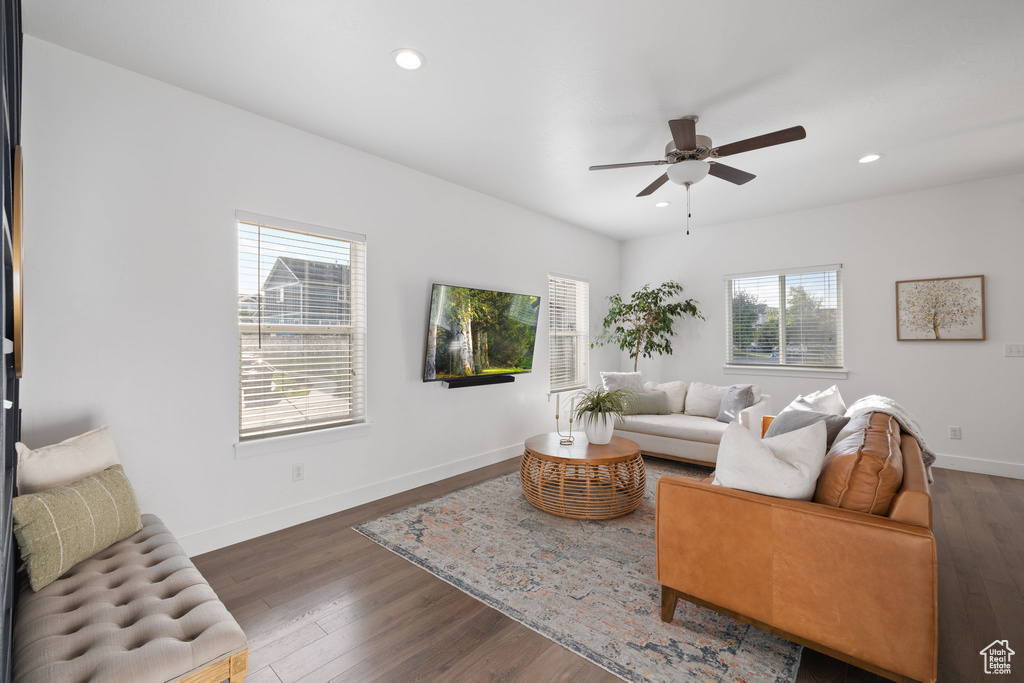 Living room with ceiling fan and dark wood-type flooring