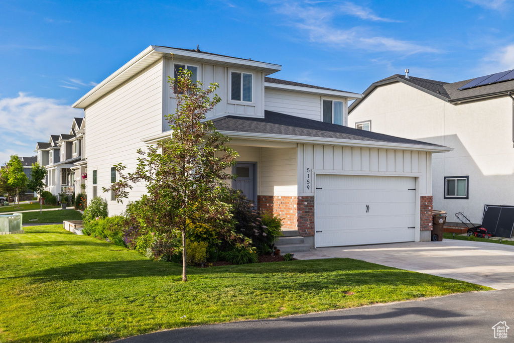 View of front of house with a garage, a front yard, and solar panels