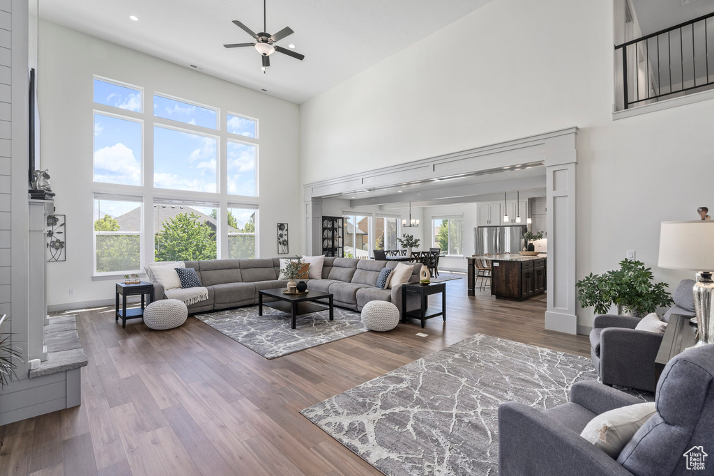 Living room with a towering ceiling, hardwood / wood-style flooring, and ceiling fan