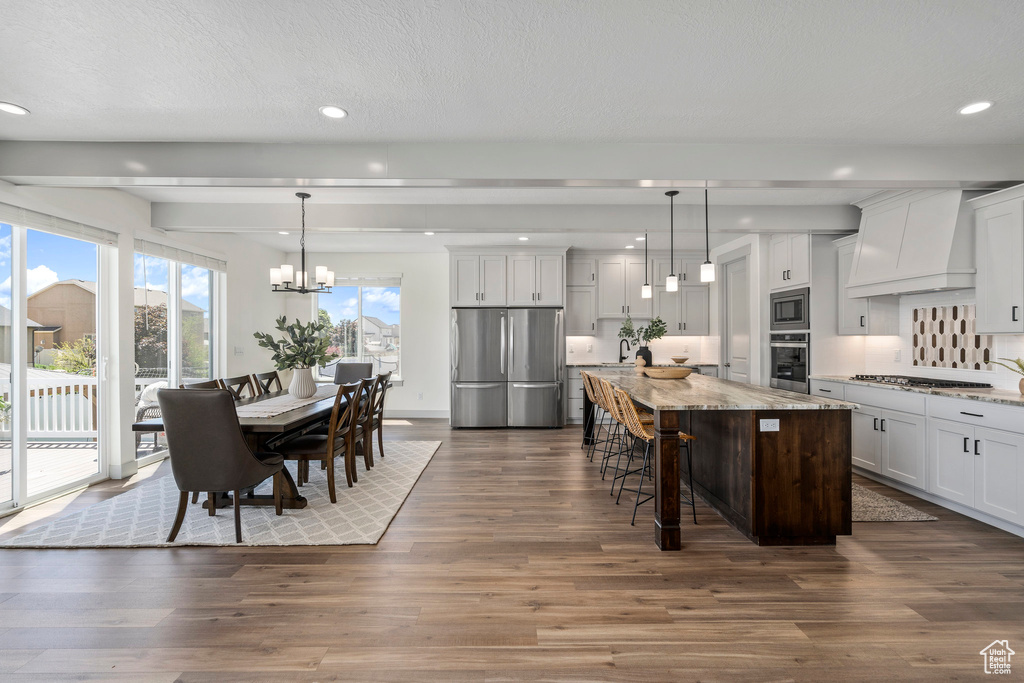 Kitchen featuring hanging light fixtures, stainless steel appliances, custom range hood, and dark hardwood / wood-style flooring