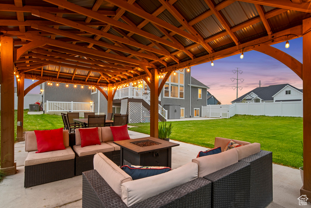 Patio terrace at dusk with an outdoor living space with a fire pit, a gazebo, and a yard